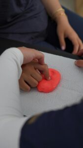 Close-up of hands manipulating putty during therapy session, emphasizing motor skills.