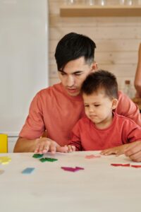 Father and son bond while playing with colorful shapes at home, showcasing family togetherness.