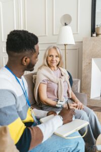 Young man and elderly woman engaging in a warm conversation indoors, both smiling.