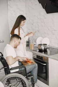A couple cooking in a kitchen, focusing on inclusivity with one partner in a wheelchair.